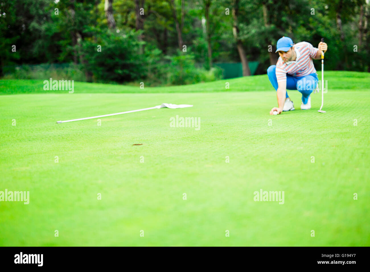 Golf player marking ball on the putting green before lifting the ball Stock Photo
