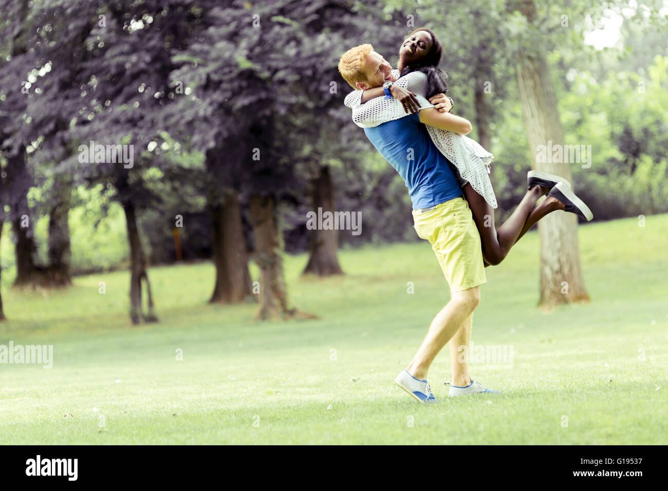 Portrait of a happy couple dancing and hugging in a park outdoors Stock Photo