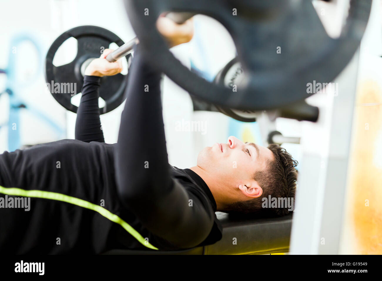 Closeup of young handsome male doing exercises on a bench press Stock Photo