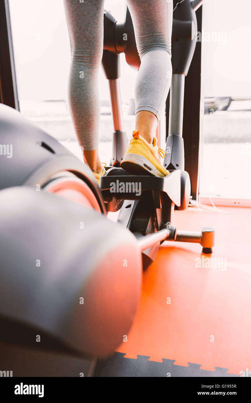 Closeup shot of legs of a female using elliptical trainer in a gym