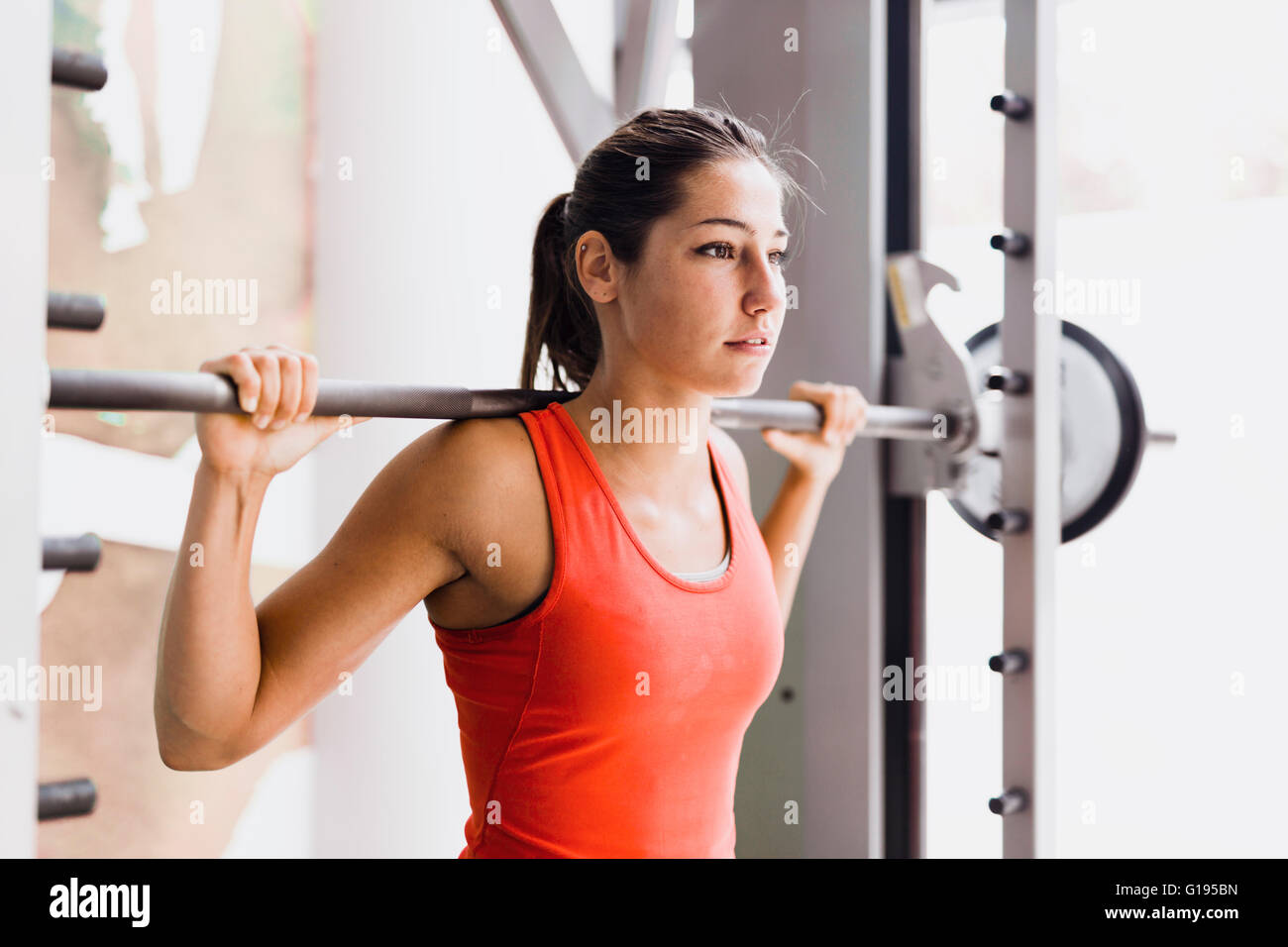 Focused young beautiful woman lifting weights in a gym Stock Photo
