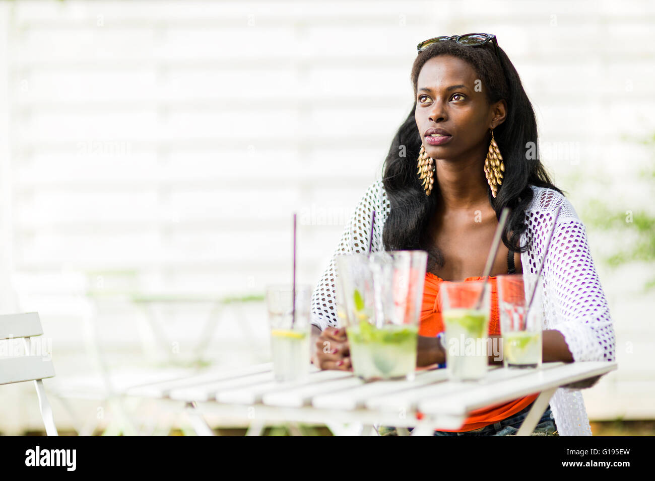 Beautiful woman is sitting at a table alone and waiting for friends Stock Photo
