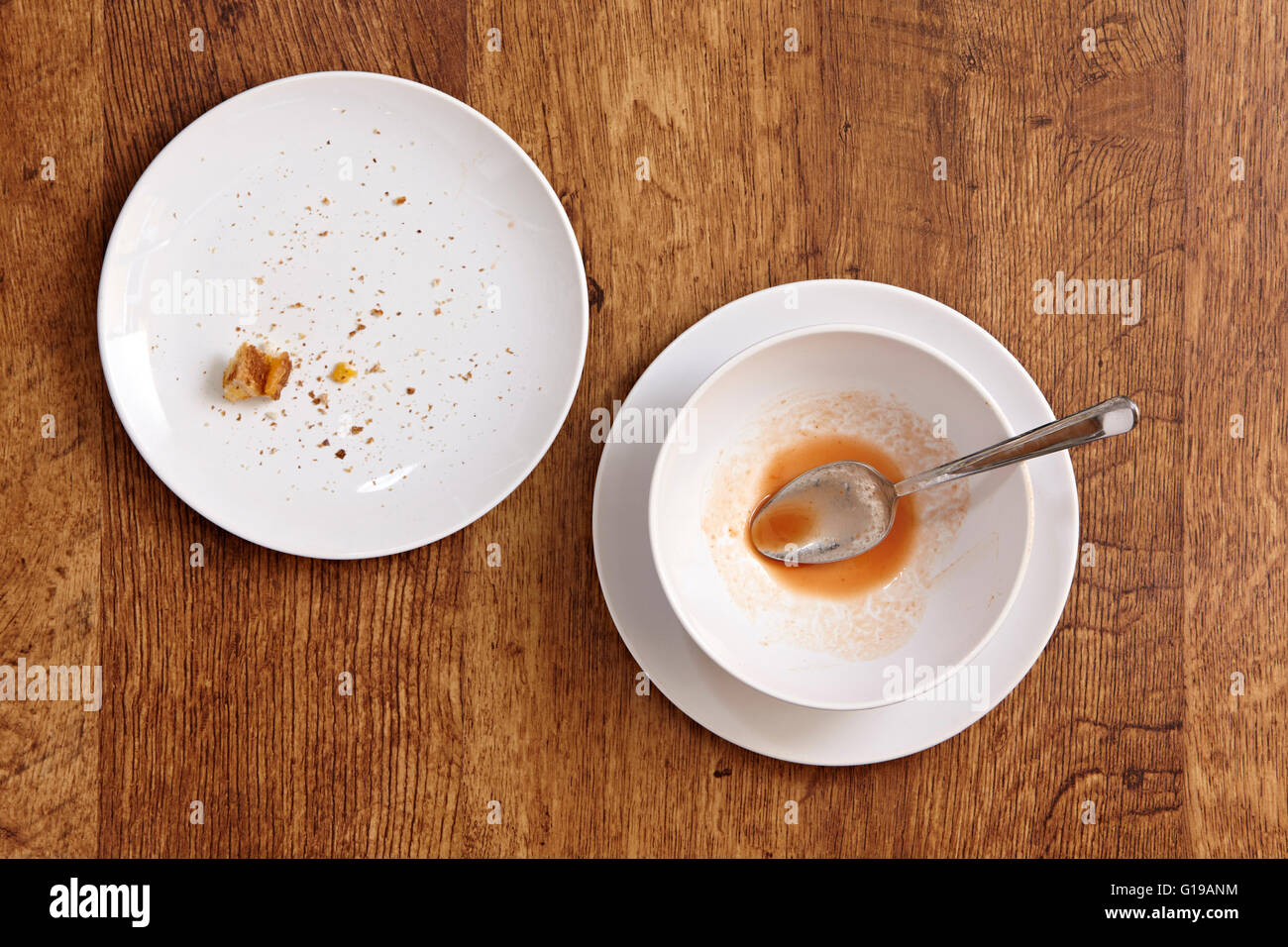 Empty soup bowl and plate with crumbs overhead on wood horizontal Stock