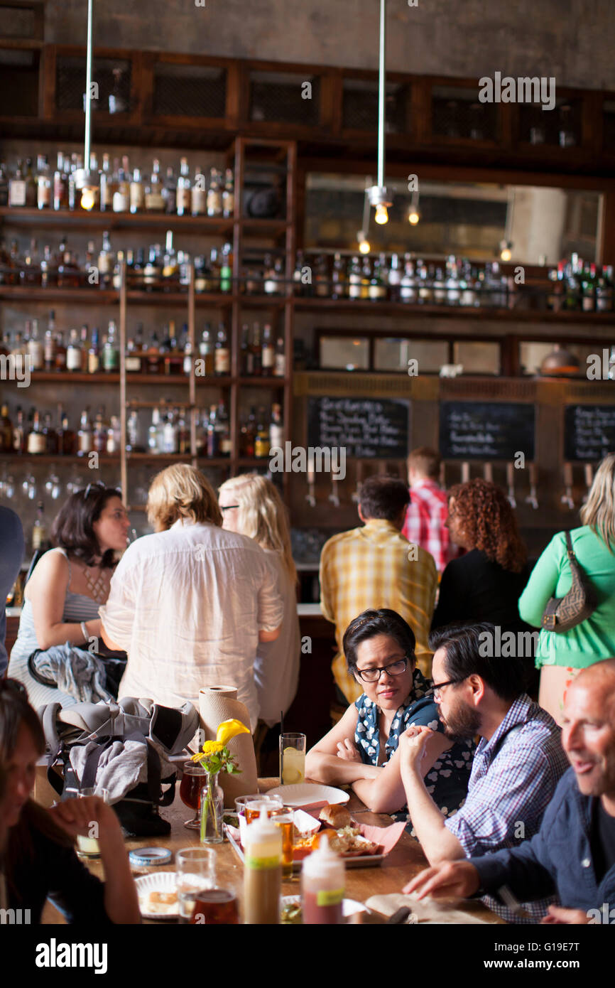 Patrons gathered at a popular new brewery in a city. Stock Photo