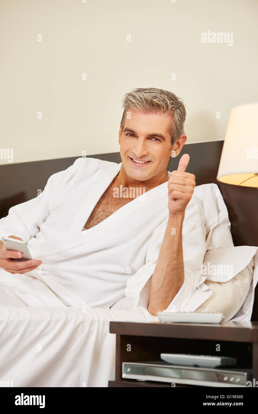 Happy elderly man in hotel room holding his thumbs up Stock Photo