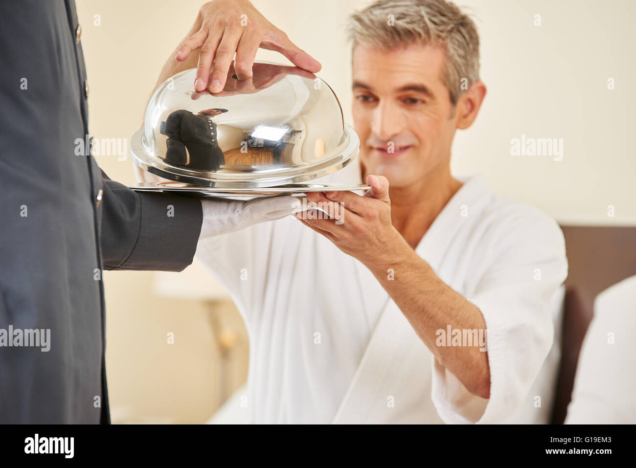 Room service bringing food in hotel room for elderly man Stock Photo