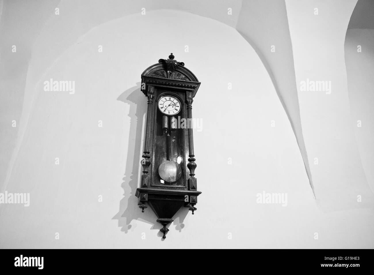 Vintage antique wood clock on wall. Black and white Stock Photo