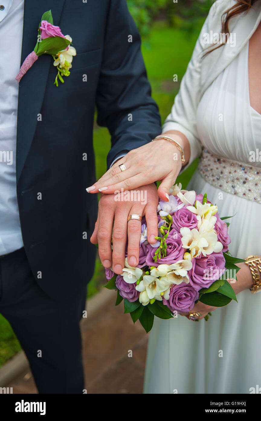 hands of the bride and groom with wedding rings on a bouquet of Stock ...
