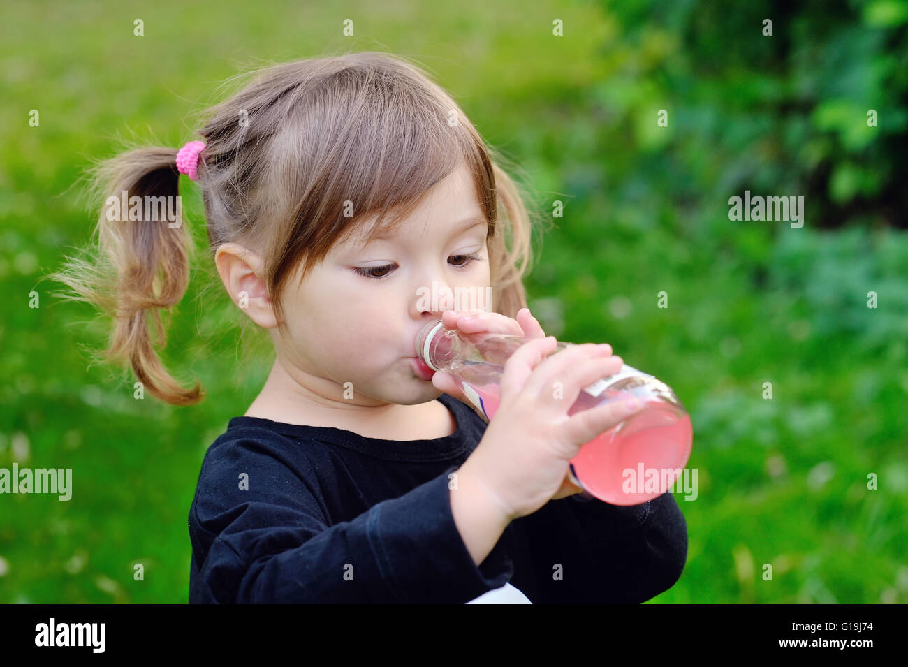 girl drinking from a bottle of lemonade, Outdoors Stock Photo
