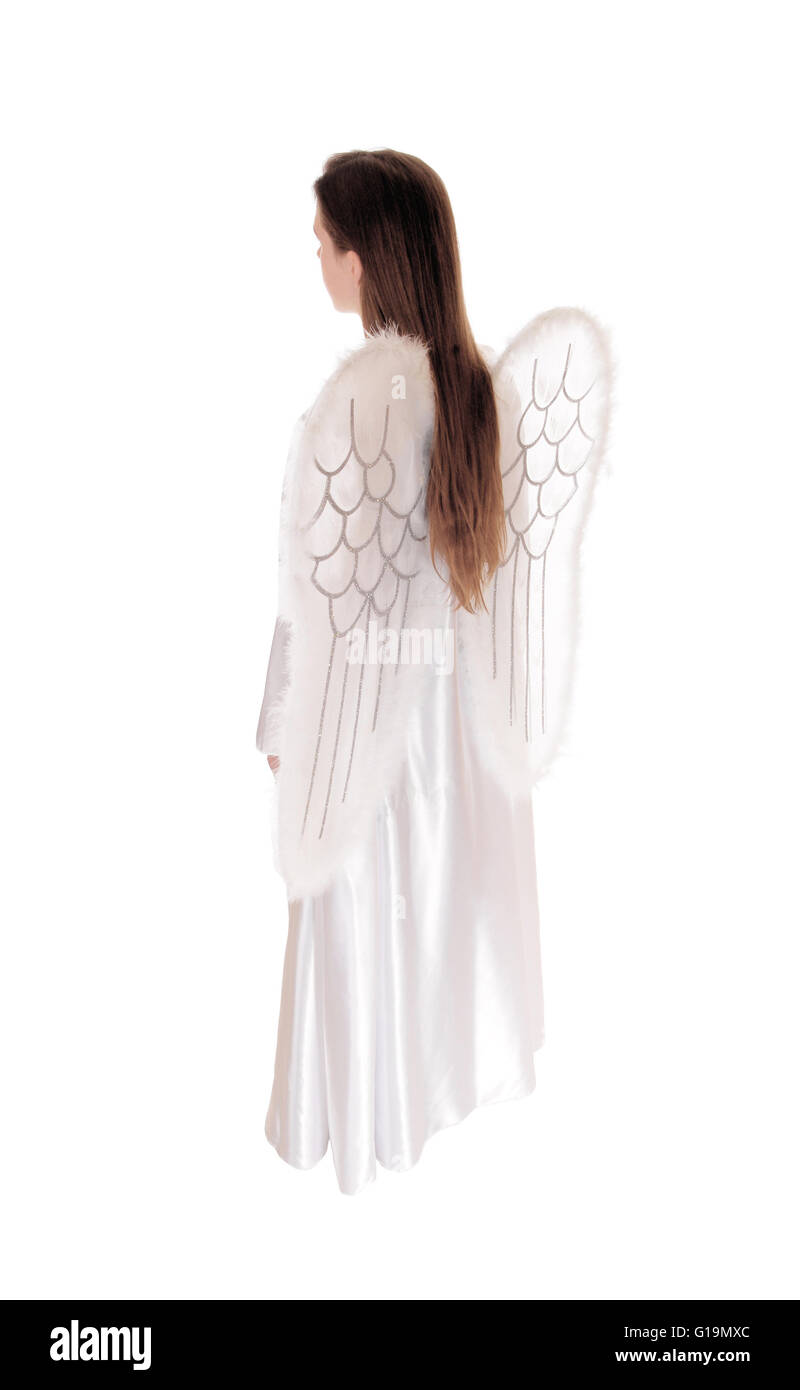 An angel in a long white satain dress with wings and long brown hair standing in profile isolated for white background. Stock Photo