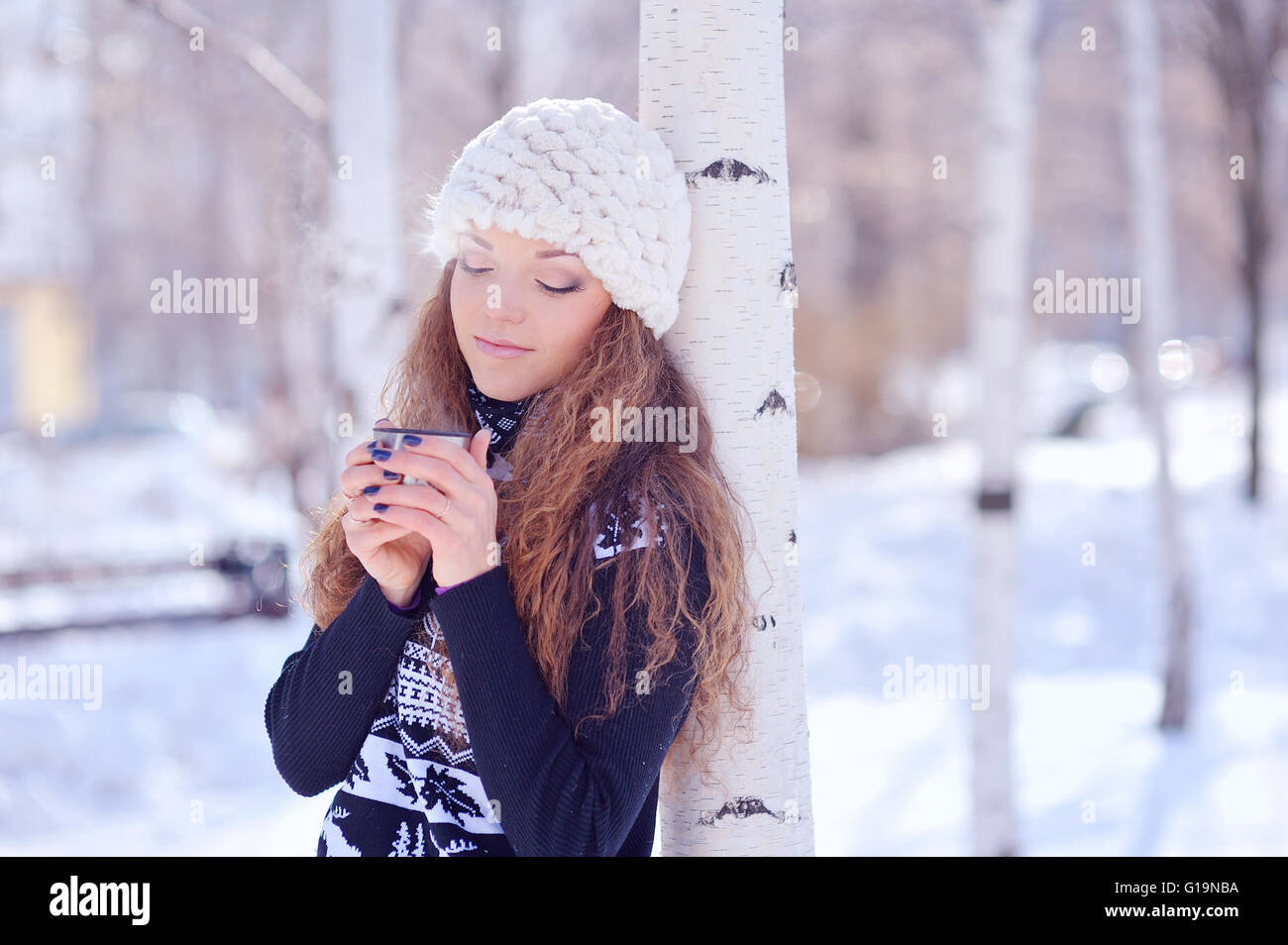 Young woman with a cup of hot drink in winter park Stock Photo