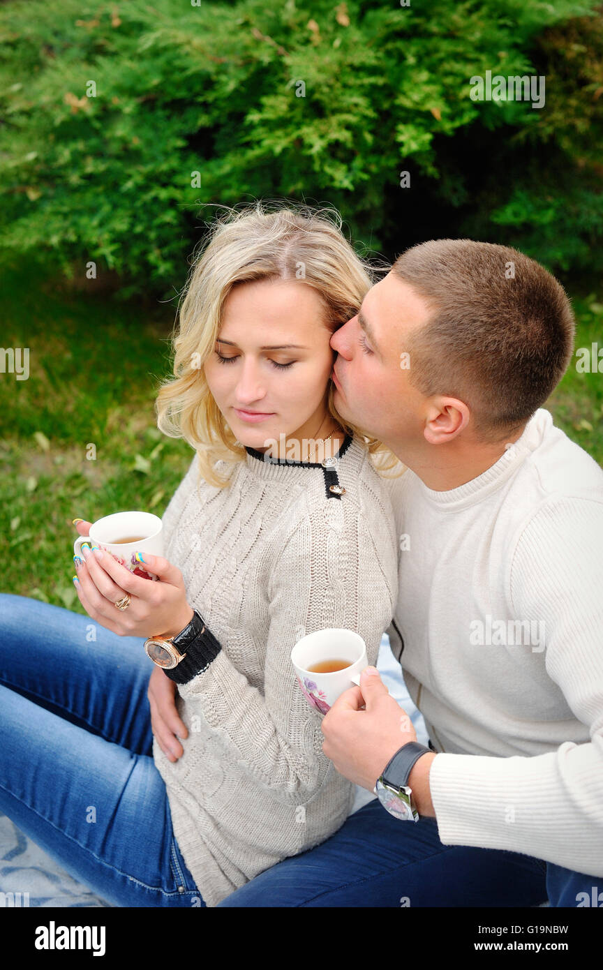 Young beautiful couple embracing under a blanket in the park. Te Stock Photo