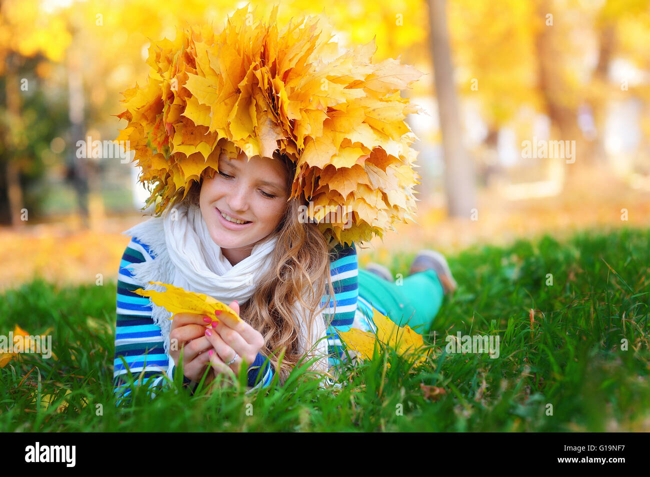 young woman sitting on gold autumn leaves, top view Stock Photo