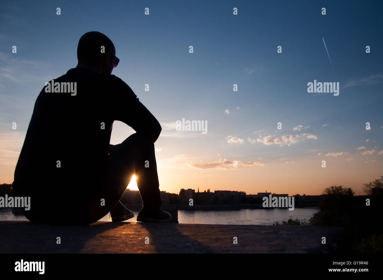 Man silhouette watching sunset over city Stock Photo - Alamy