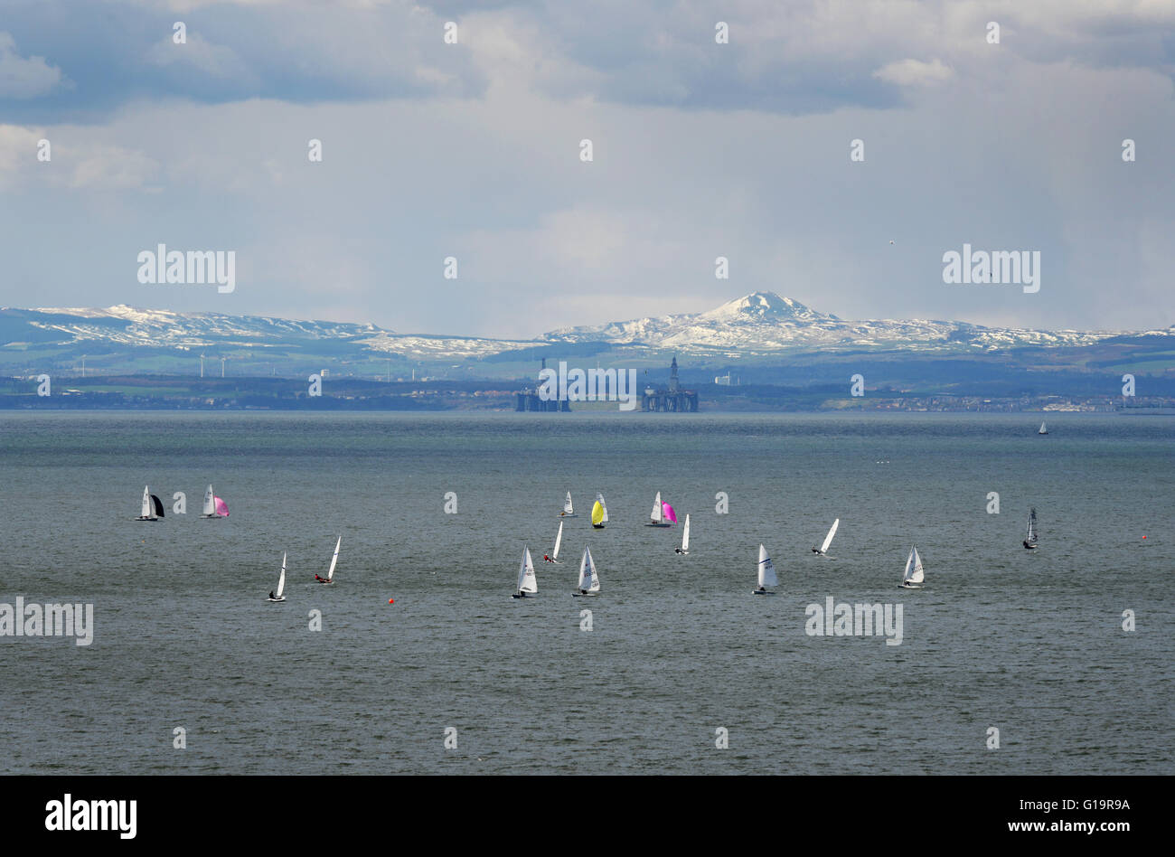 Dingies bobbing up and down looking across the Firth of Fourth towards unused oil-rigs and the Lomond Hills beyond. Stock Photo