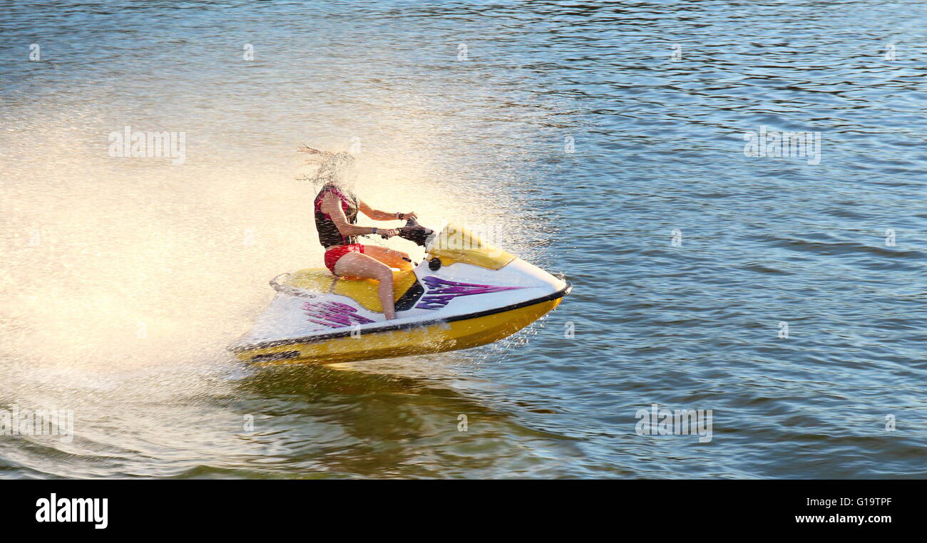 Adult having fun jumping a wave riding yellow and white jet ski in
