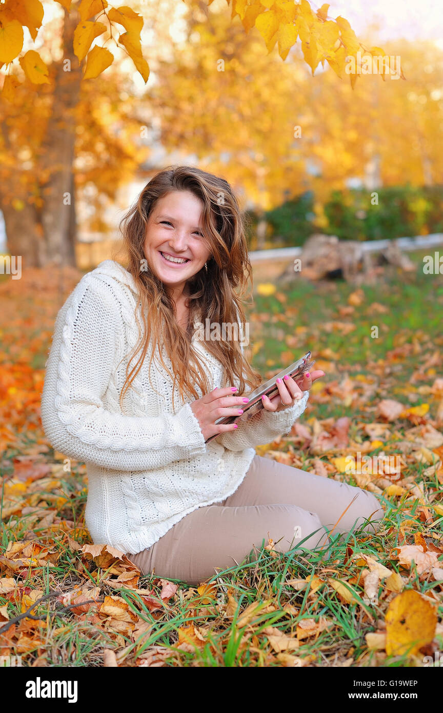 beautiful girl in autumn park with a tablet Stock Photo