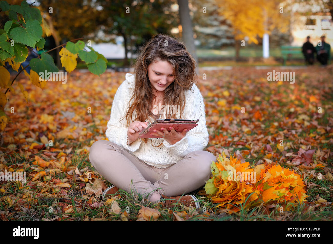 beautiful girl in autumn park with a tablet resting Stock Photo