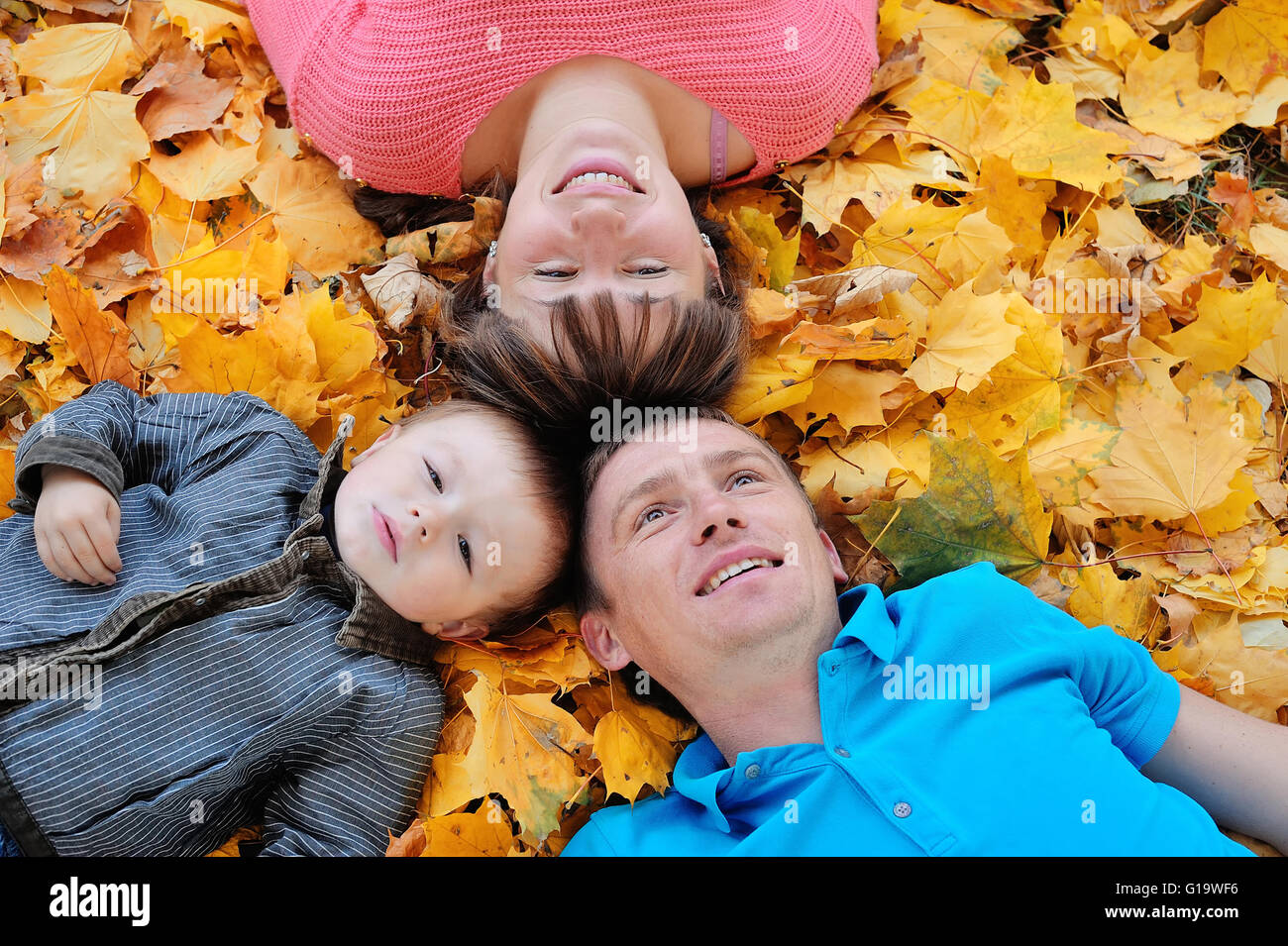 happy family, mother, father and son lying on the autumn leaves Stock Photo