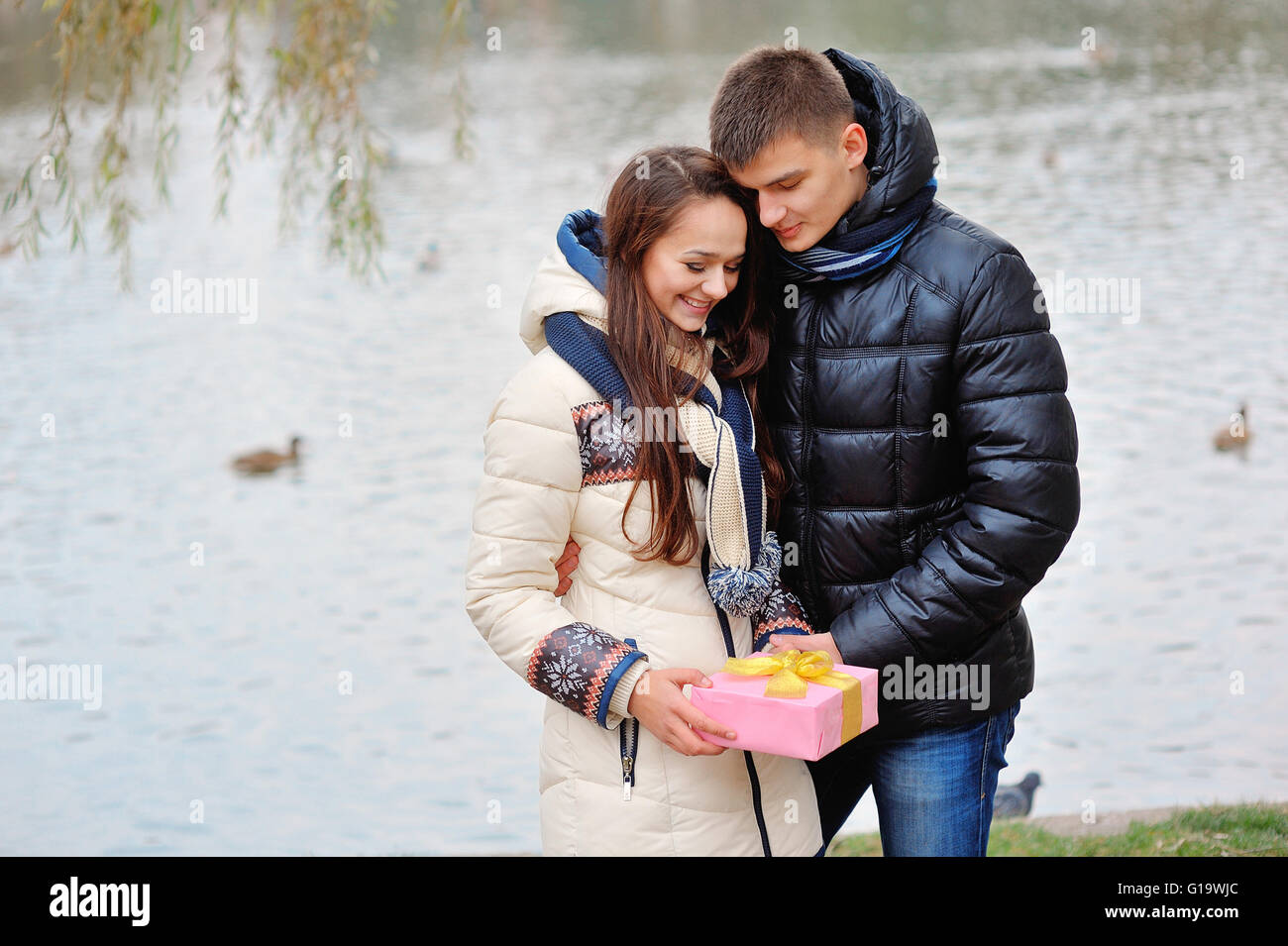 The young man gives a gift to a young girl in the cafe and they Stock Photo