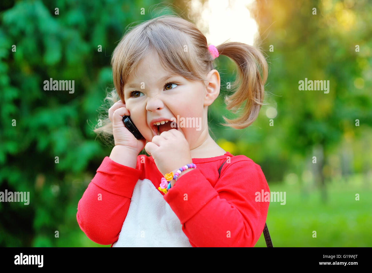Little girl shouting into the phone in a park Stock Photo