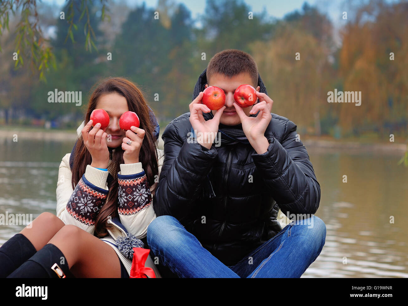 Happy Couple in Autumn Garden.Having Fun on the Grass and Eating Stock Photo