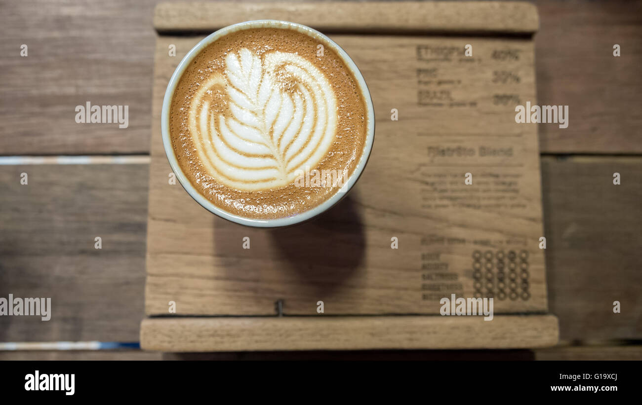 Coffee with white leaf latte art on wooden board Stock Photo