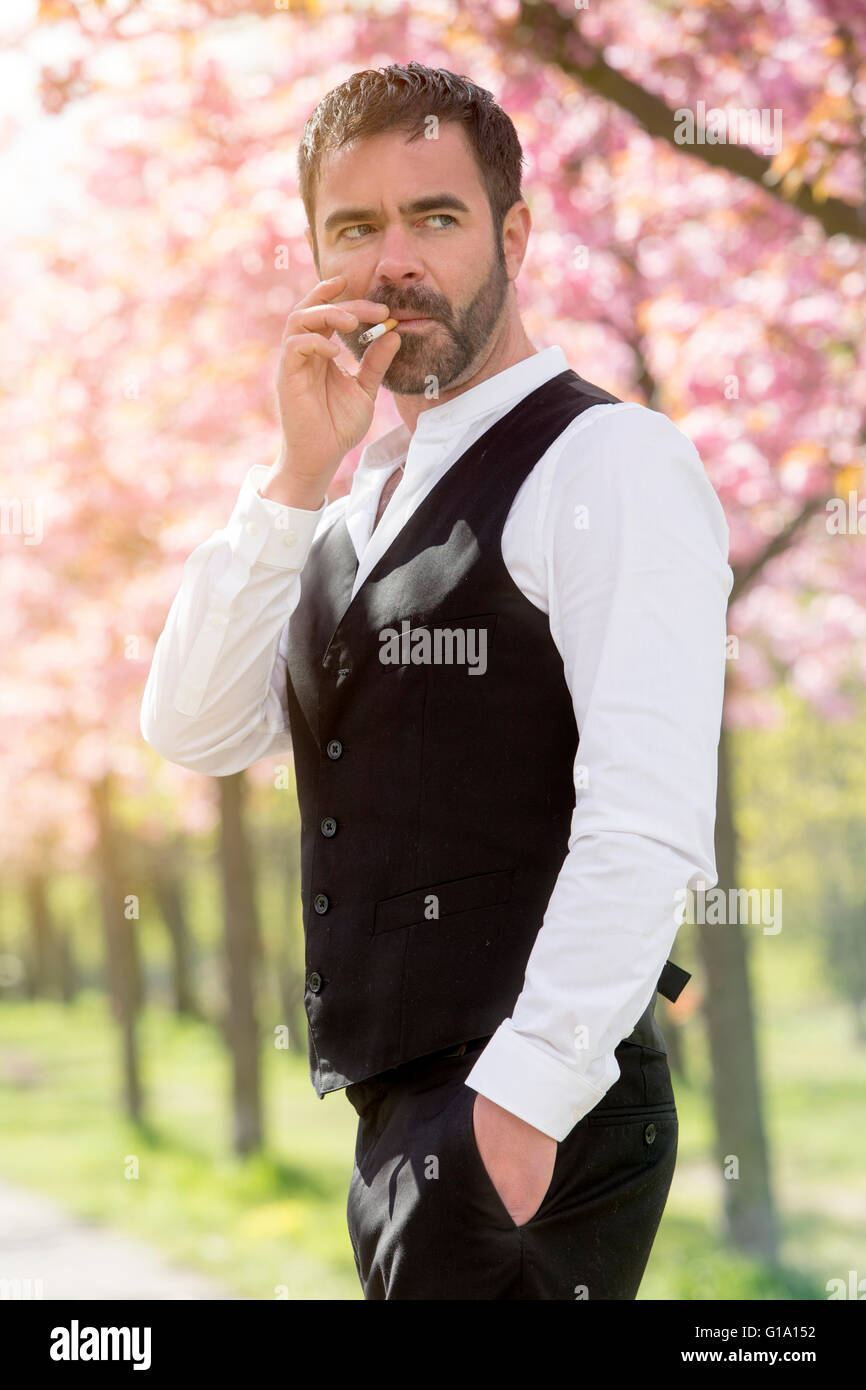 handsome businessman smoking a cigarette outside Stock Photo