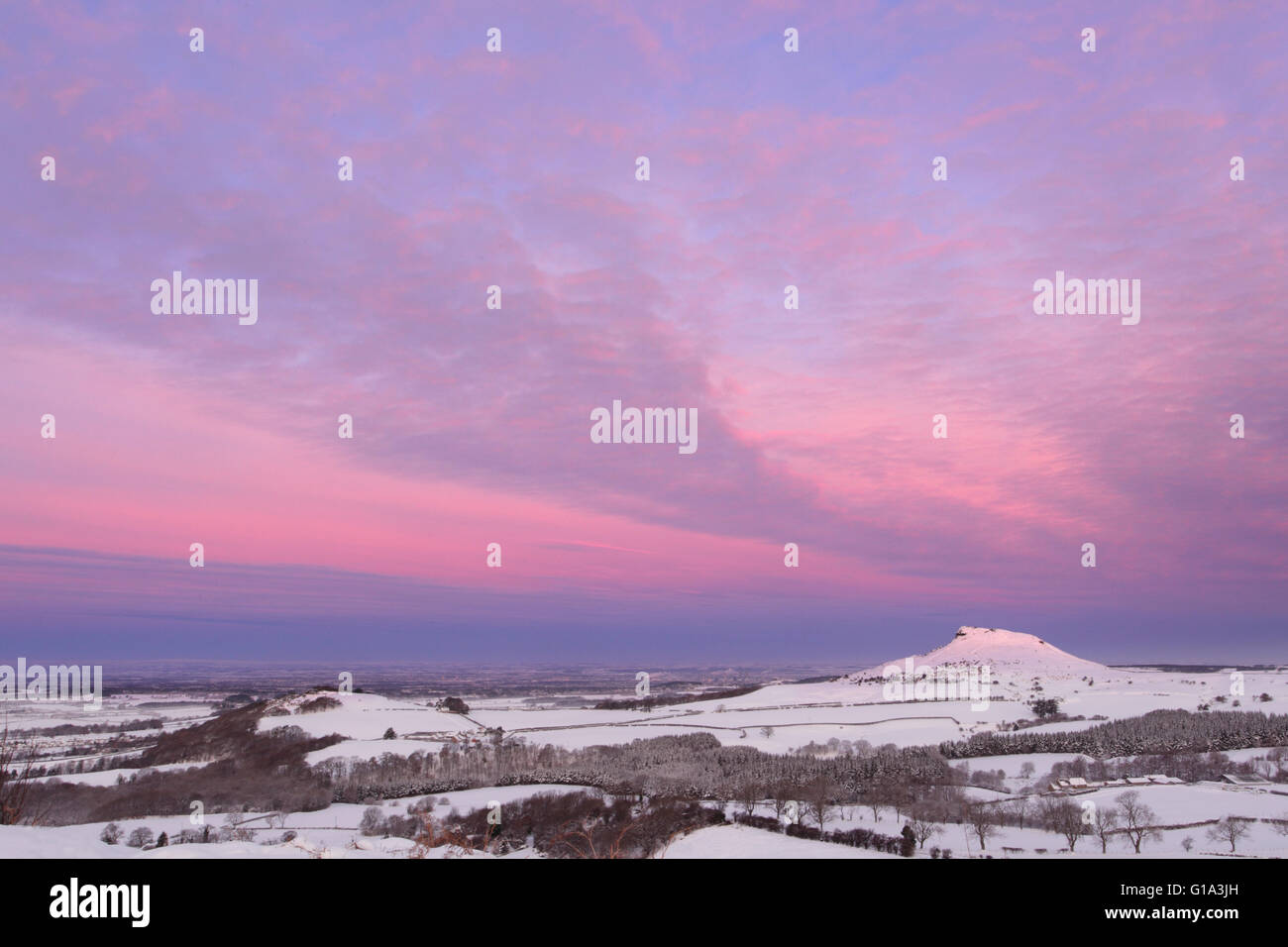 Roseberry Topping at daybreak in winter, covered in snow and cloud picking up dawn colours Stock Photo