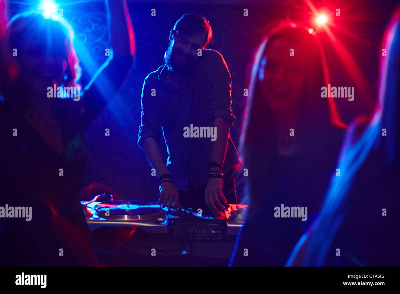 Deejay enjoying music with dancing friends in front Stock Photo - Alamy