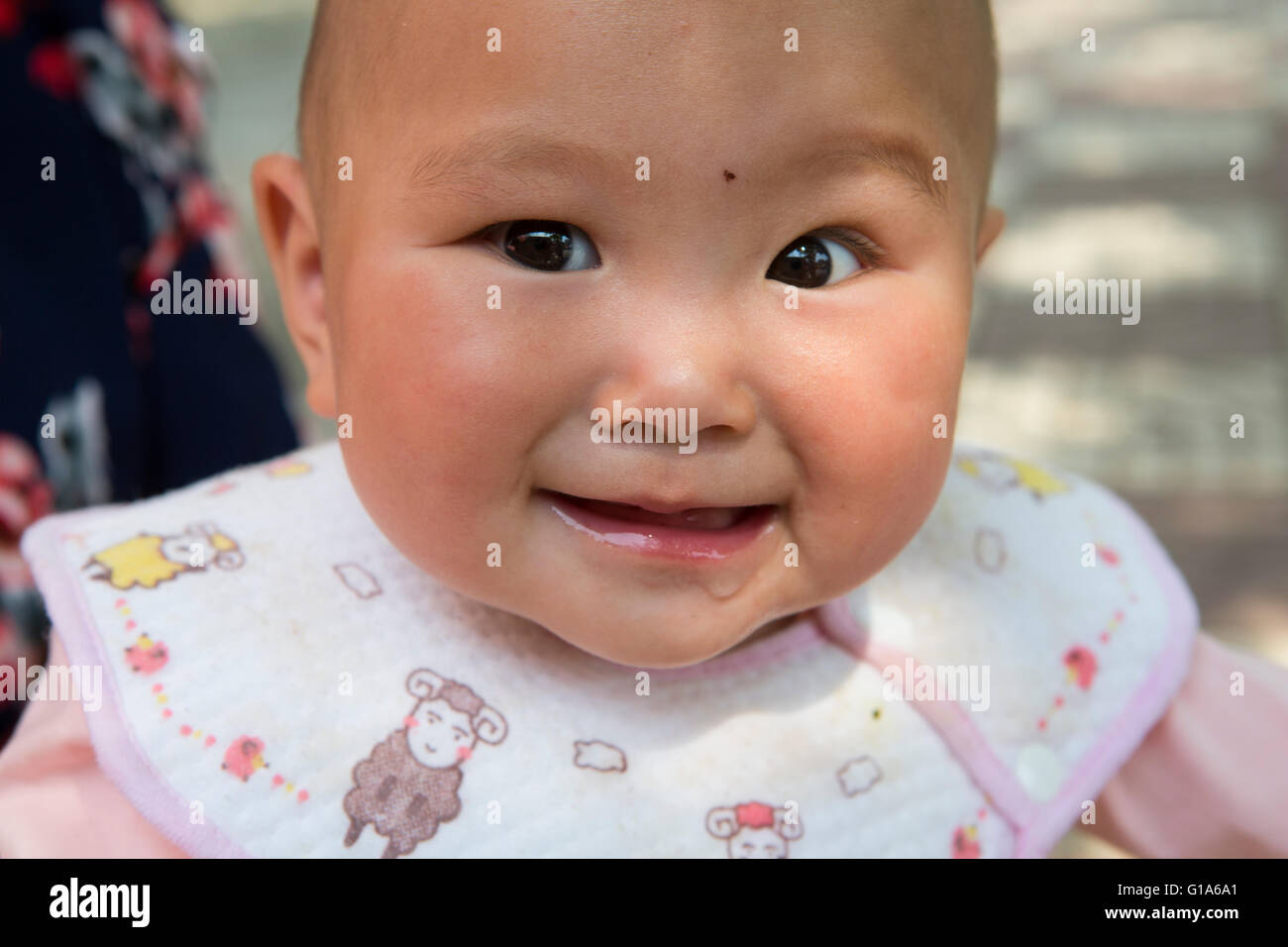Portrait of a cute happy adorable smiling Chinese baby girl with pink clothes in Nanjing, China. Stock Photo