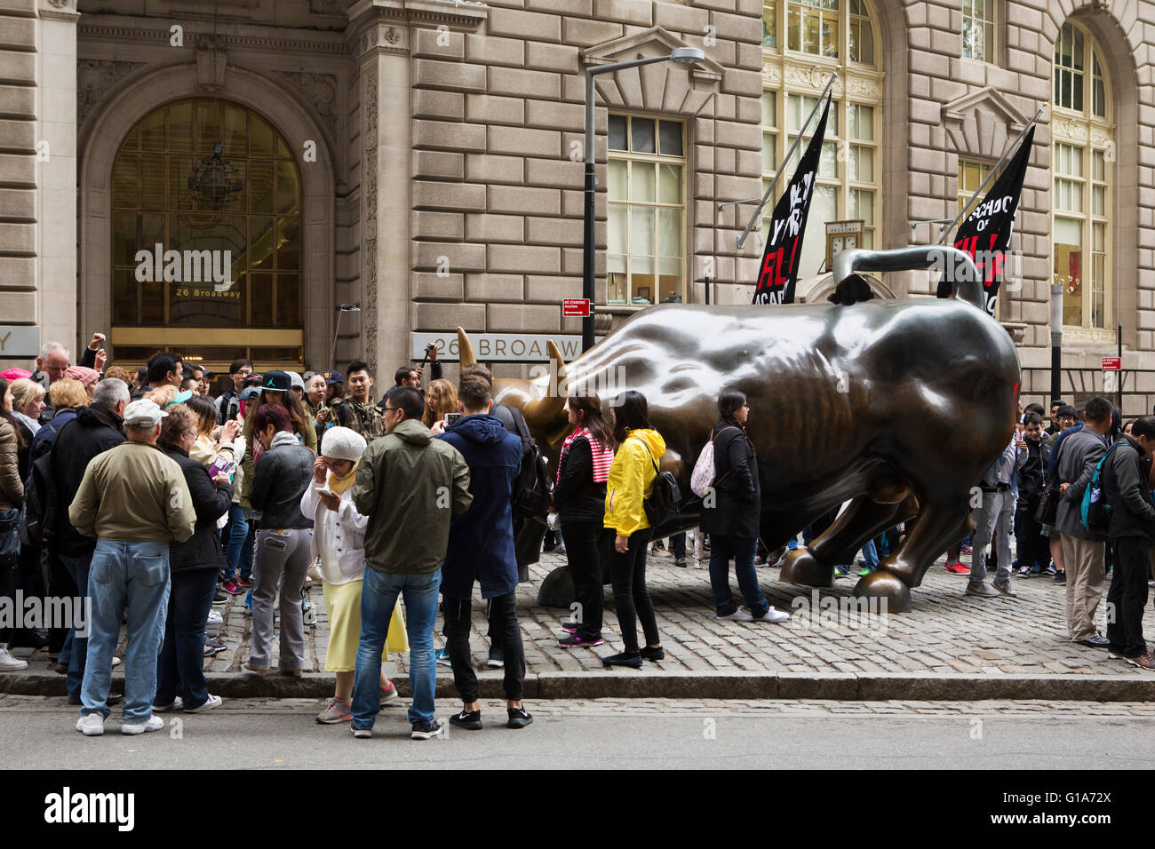A crowd gathers around the bull statue on Wall Street in New York City