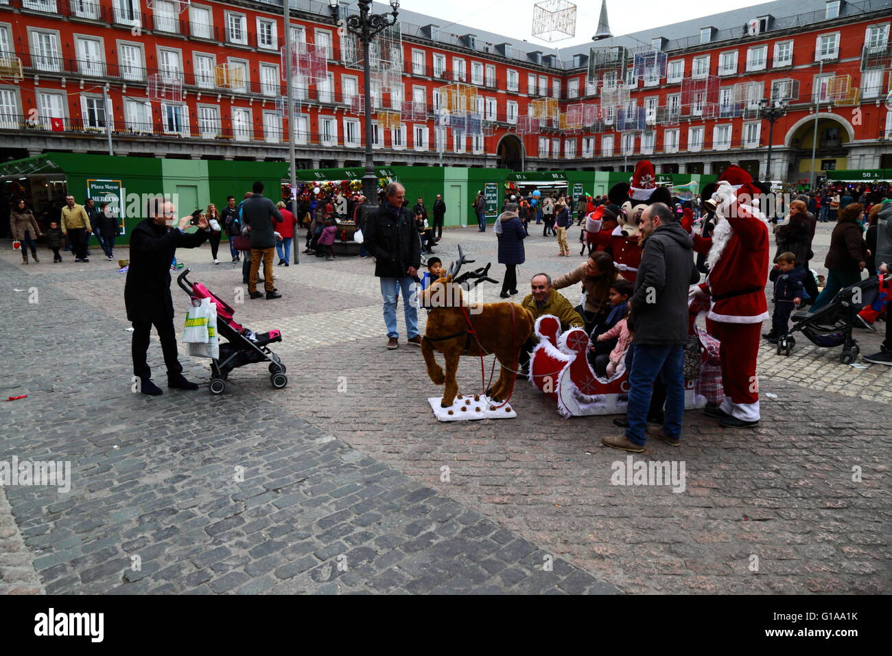 Family have their photo taken with Santa, sleigh and reindeer in Christmas market, Plaza Mayor, Madrid, Spain Stock Photo