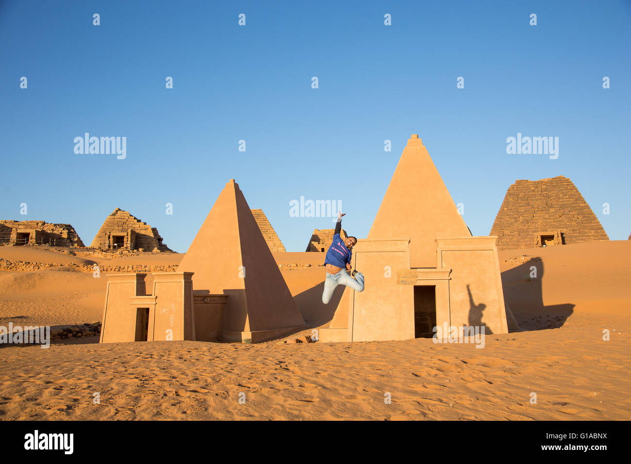 a young man jumping in front on Meroe pyramids in Sudan Stock Photo