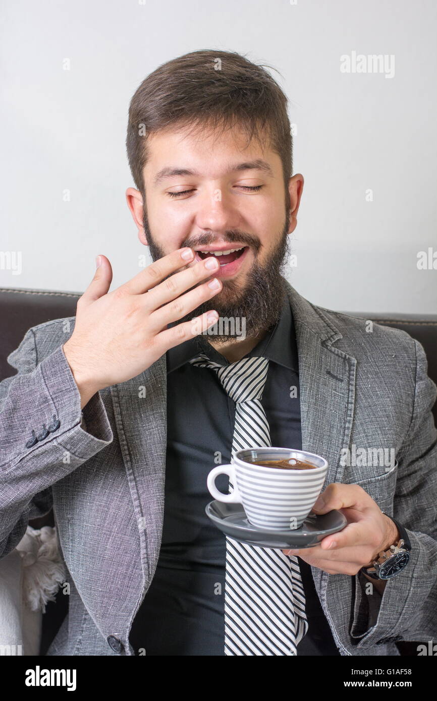Sleepy businessman in a suit with a cup of coffee Stock Photo