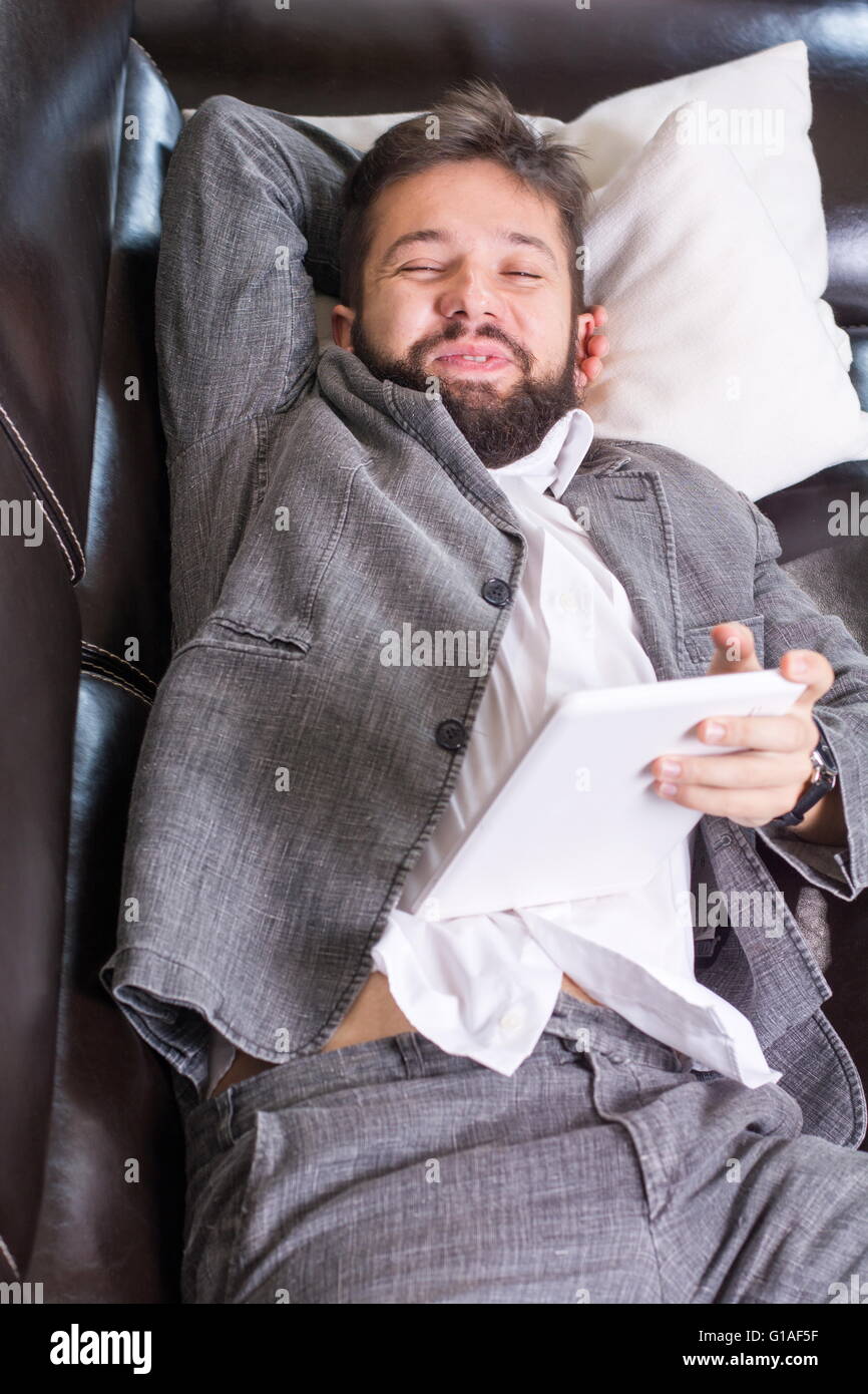 Sleepy businessman with a tablet device on a  sofa Stock Photo