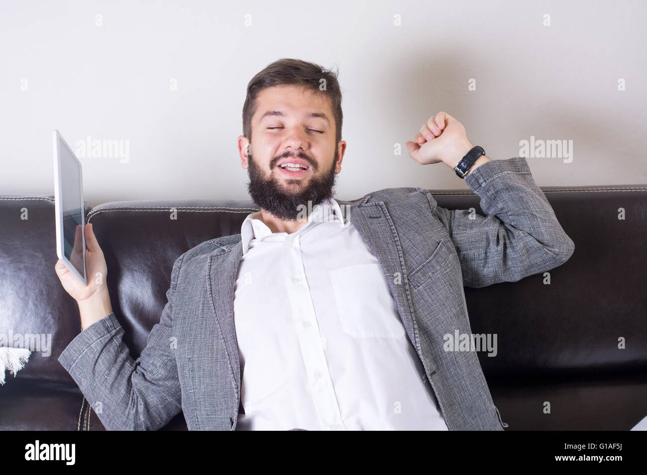Sleepy businessman stretching with a tablet device Stock Photo