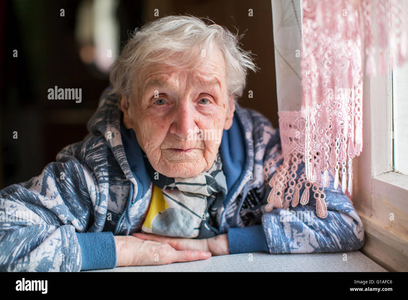 Sad elderly woman portrait at the table. Stock Photo