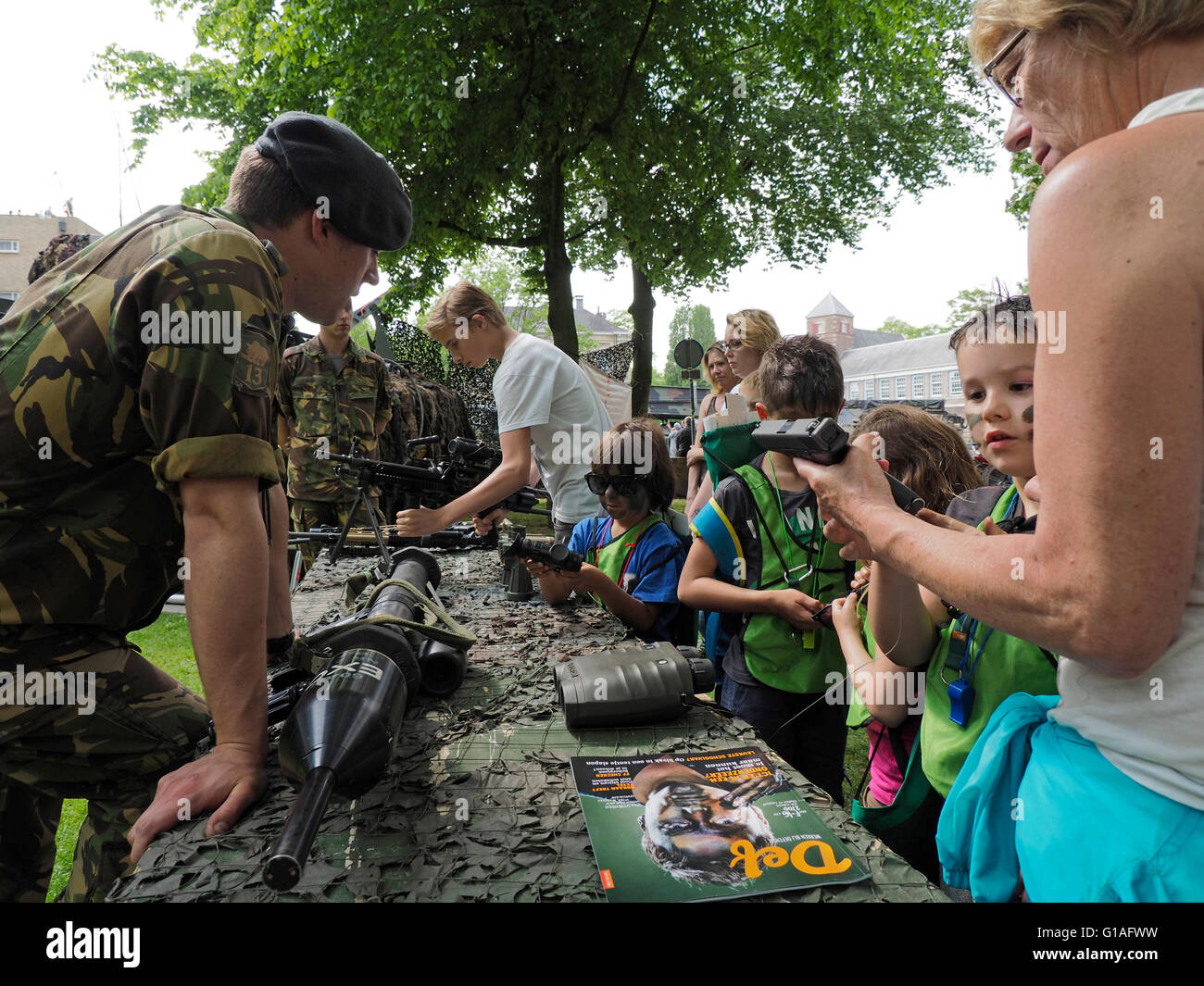 Dutch army soldier showing various arms and weaponry to civilians and children in the Valkenberg park, Breda, the Netherlands. Stock Photo