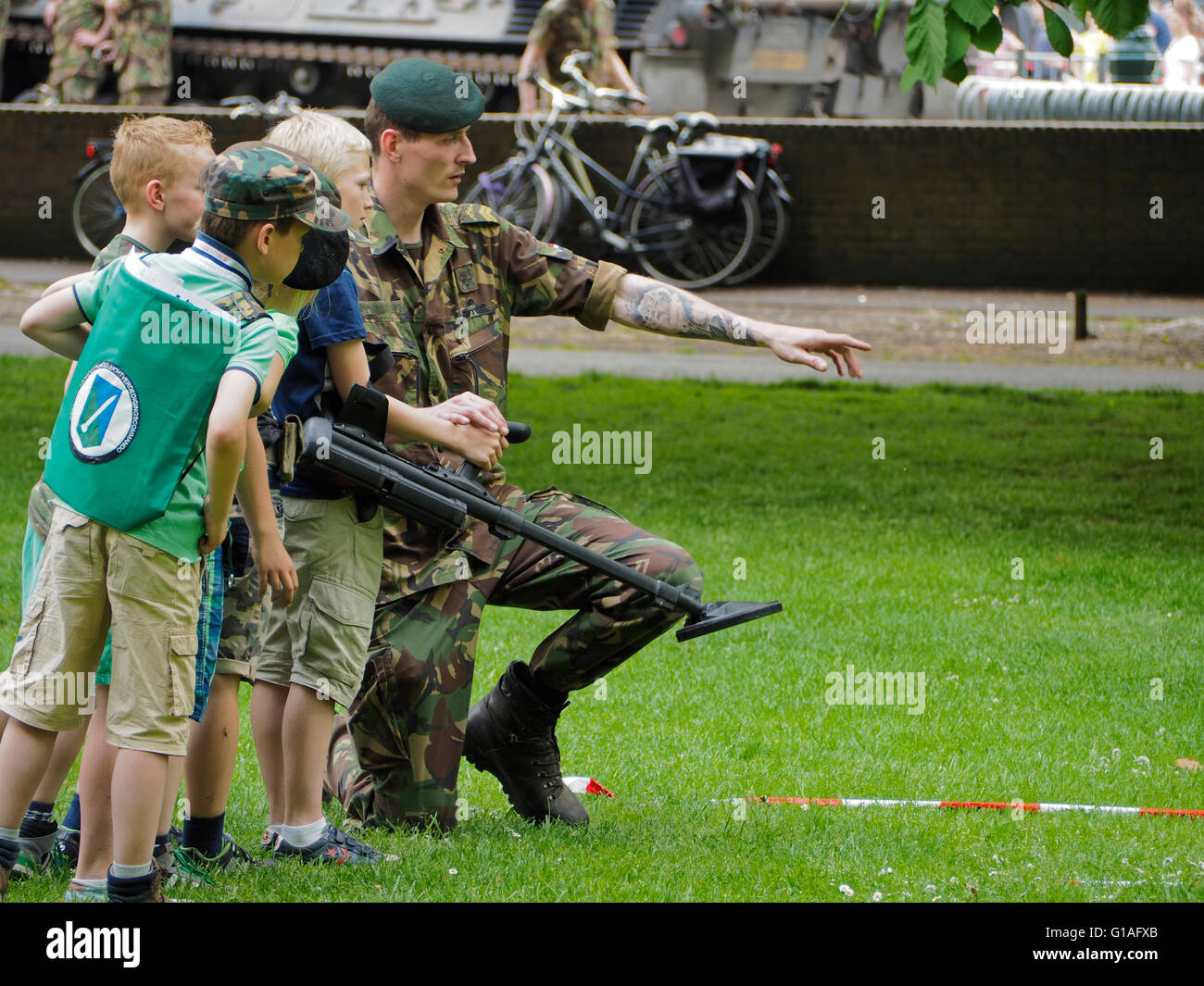 Royal Dutch army soldier showing kids boys children how a metal detector works, Valkenberg park, Breda, the Netherlands Stock Photo