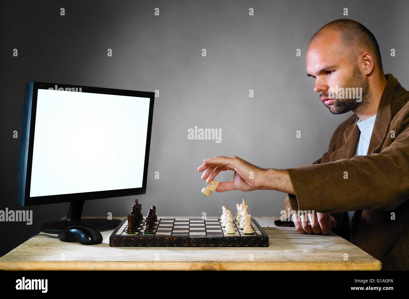 Man playing chess against computer Stock Photo