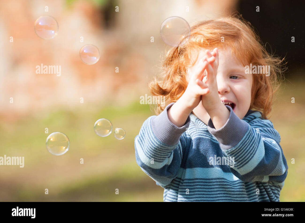 Happy girl trying to catch soap bubble Stock Photo