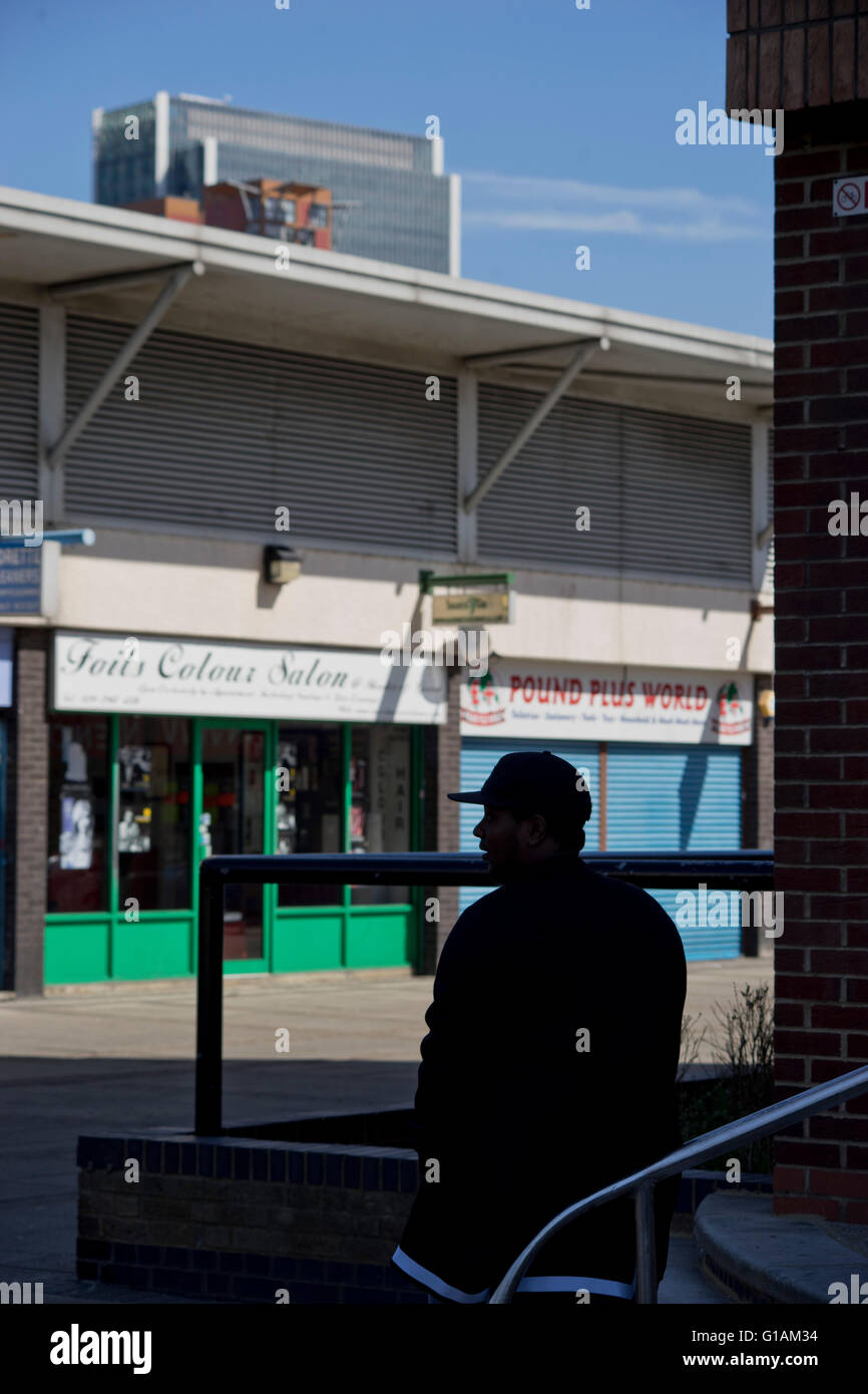 Man sitting outdoors in a poor neighbourhood in Docklands next to Canary Wharf. London, UK Stock Photo