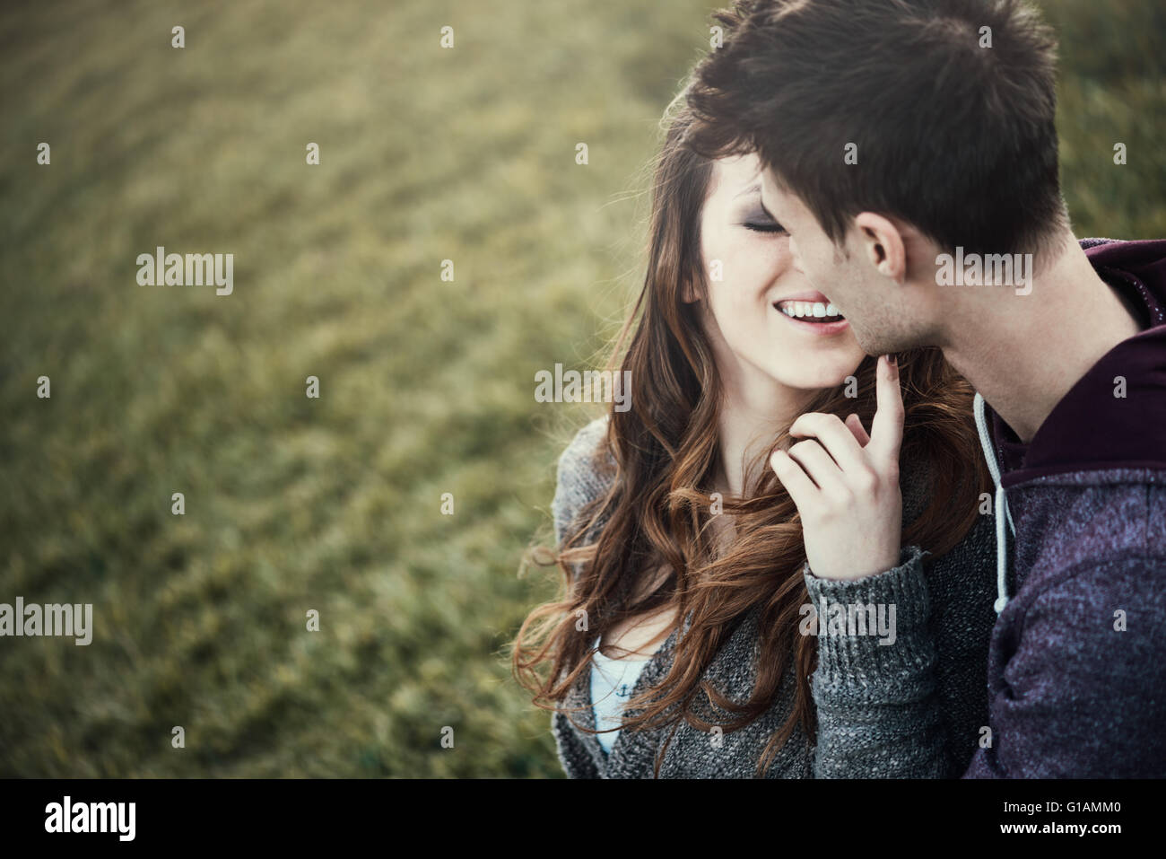 Young loving couple sitting on grass, she is flirting with him, love and relationships concept Stock Photo