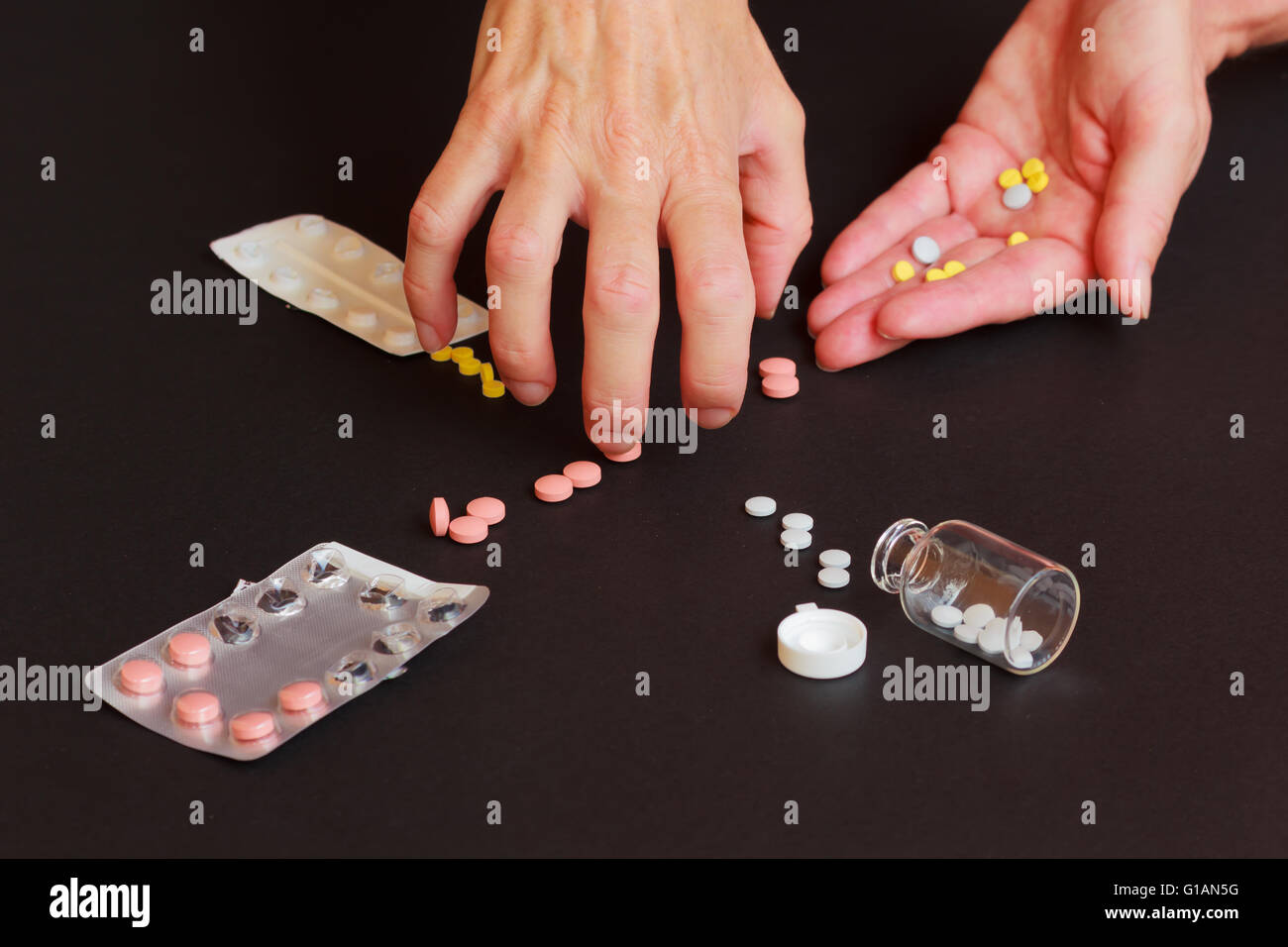 a woman collects too many tablets from jars and blisters Stock Photo