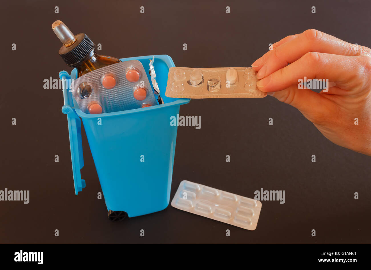 a hand throws an expired drugs into the  trash bin Stock Photo