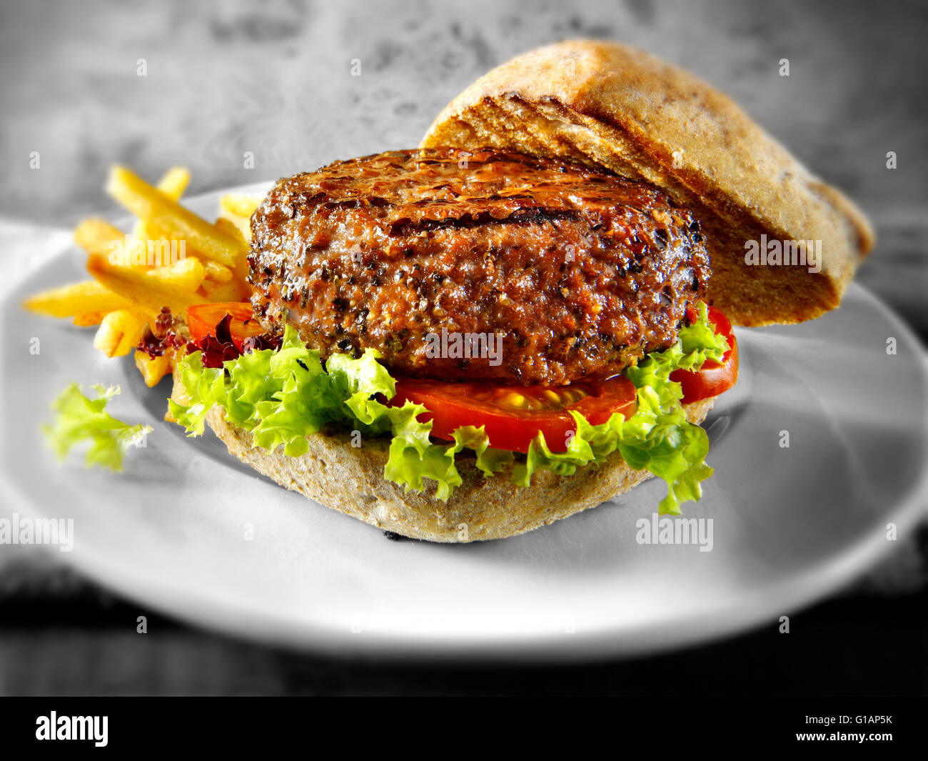 Beef burger or hamburger in a with wholemeal bun with chips Stock Photo