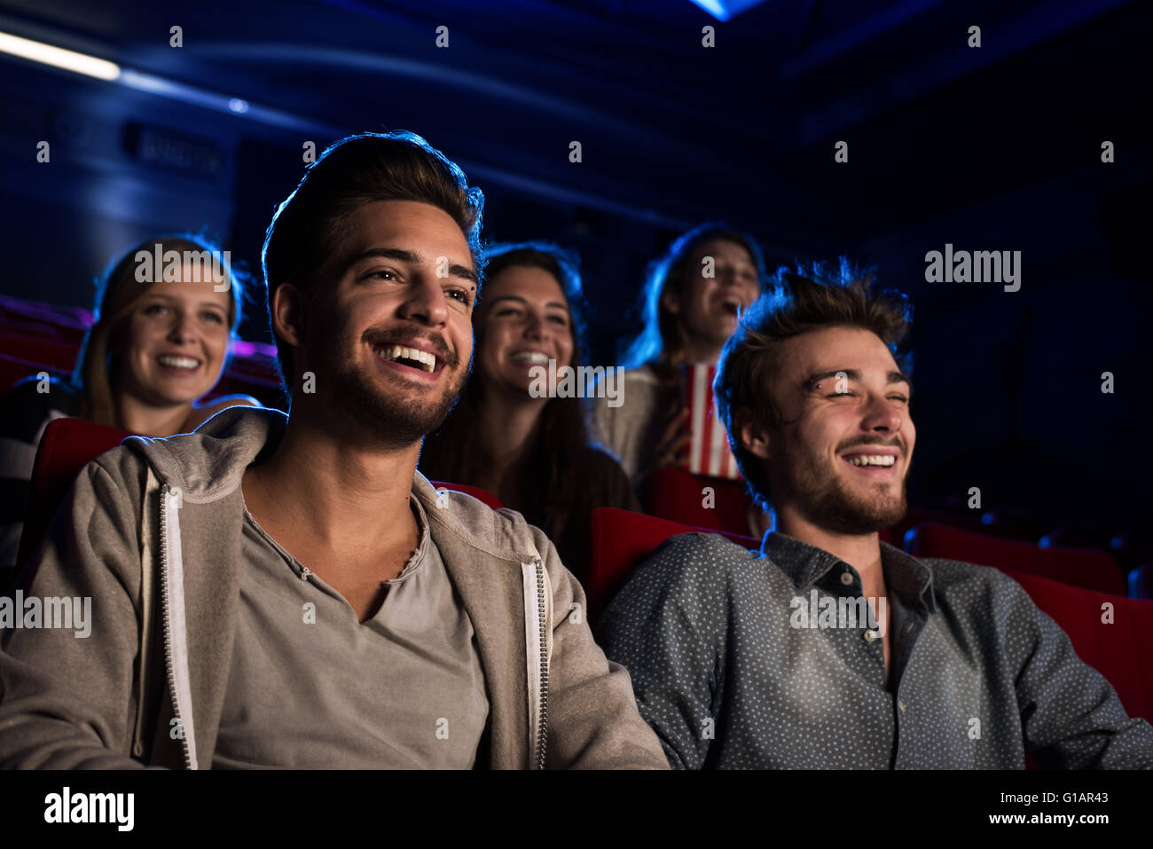Happy friends at the cinema watching a movie together, entertainment and leisure concept Stock Photo