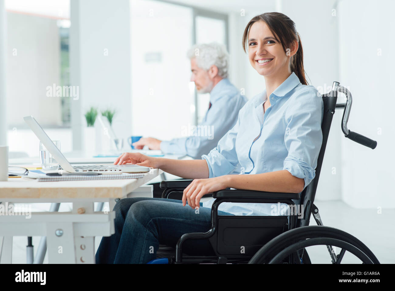 Confident happy businesswoman in wheelchair working at office desk and