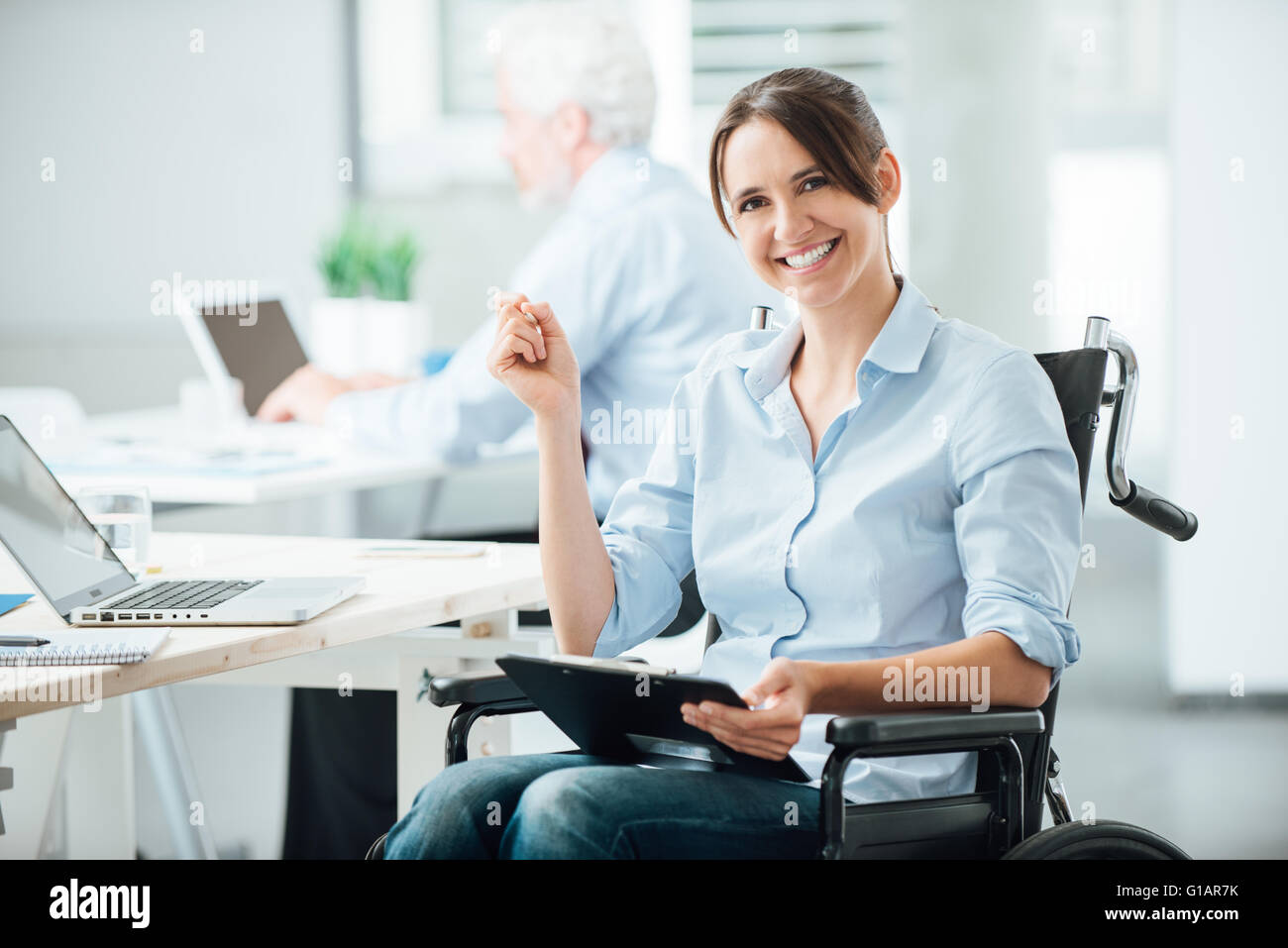 Happy female office worker in wheelchair holding a clipboard and smiling at  camera, disabled people support at workplace Stock Photo - Alamy